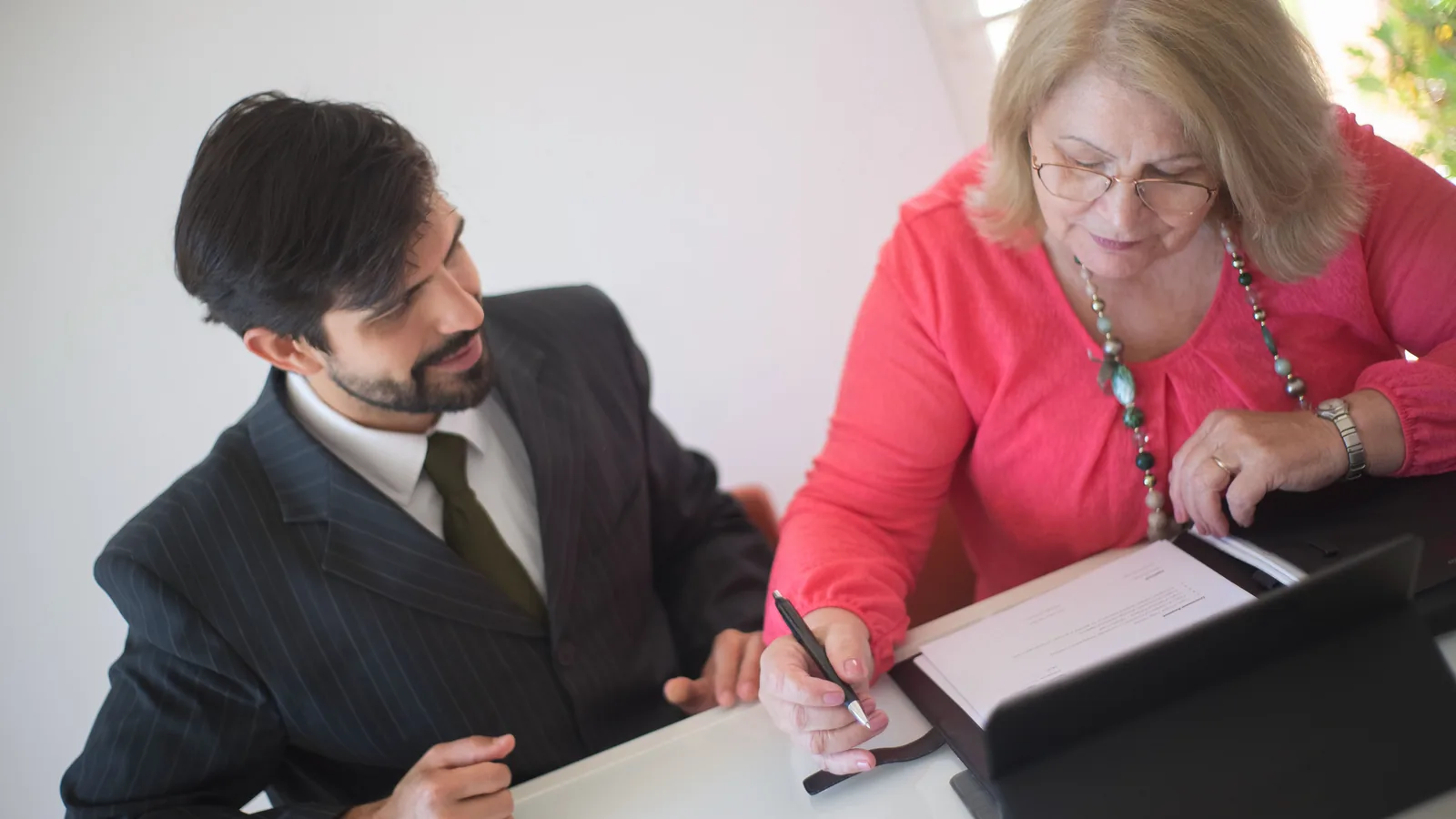Femme âgée signant des documents avec l'aide d'une professionnelle